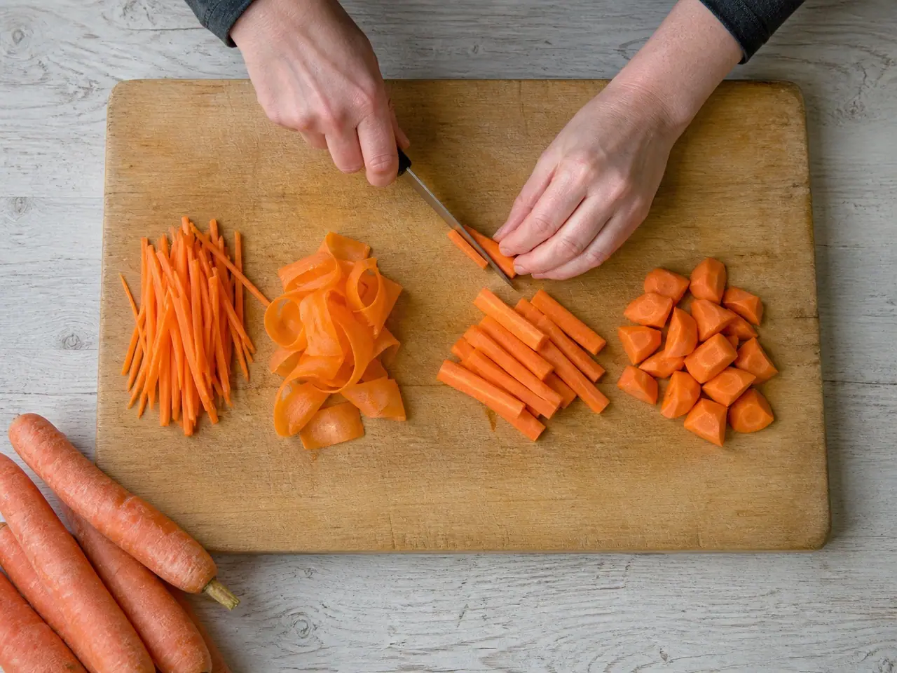 Hands cutting carrots into different shapes for dinner