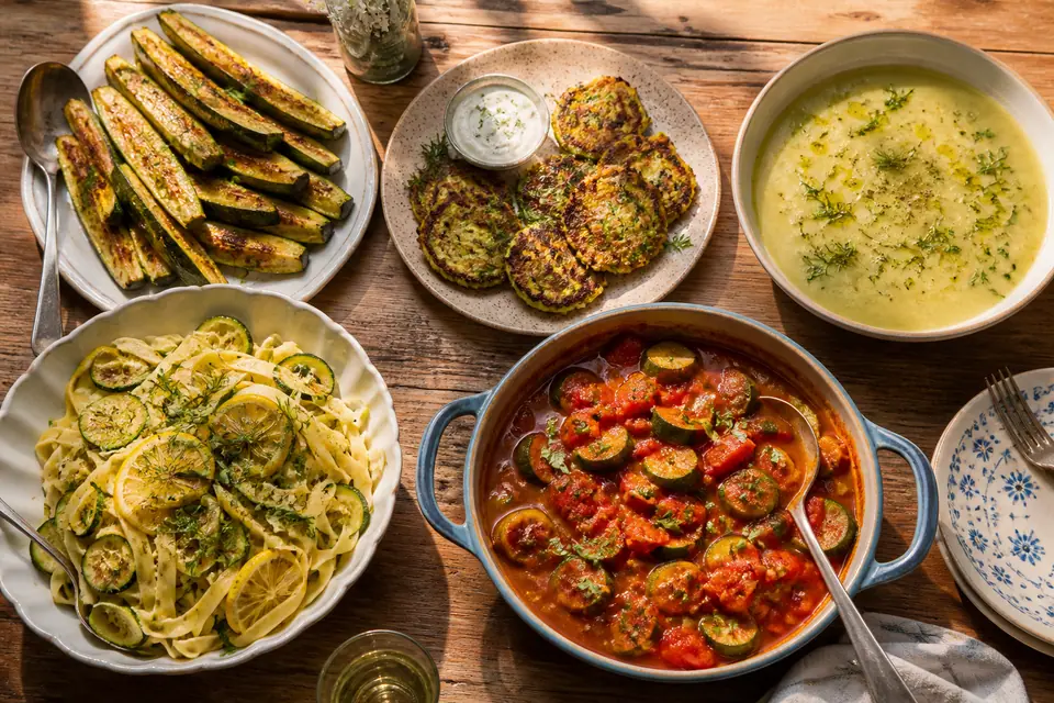 Five different courgette dinners on a wooden kitchen table