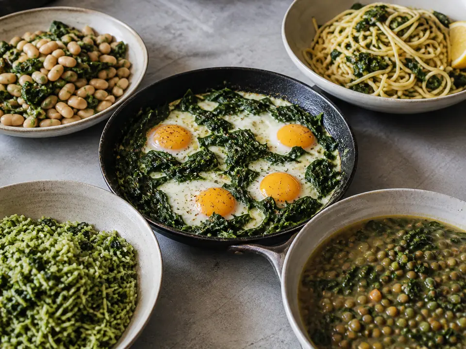 Five spinach dinners around a skillet of eggs and wilted greens