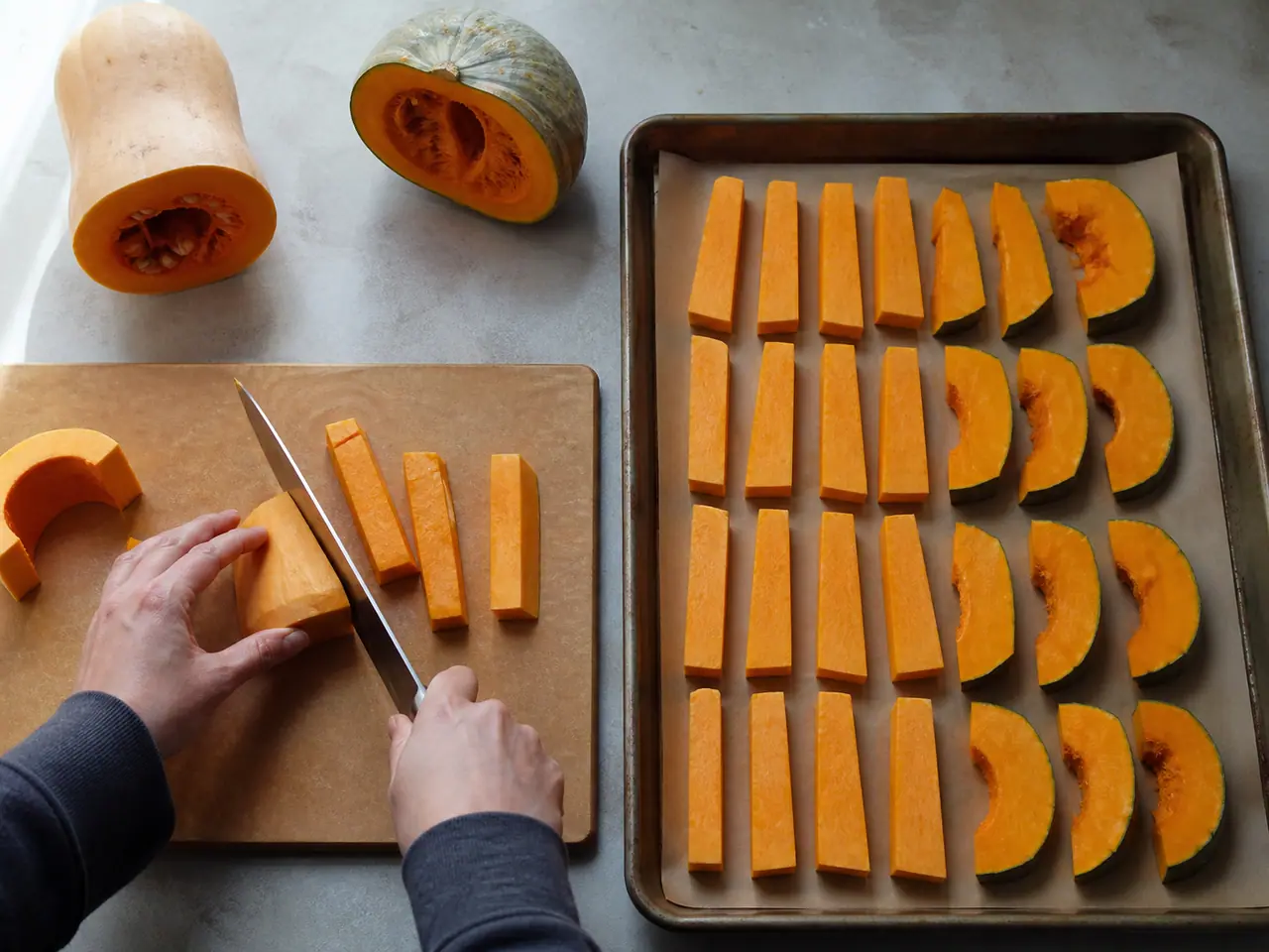 Hands cutting pumpkin and butternut squash into matching roasting wedges