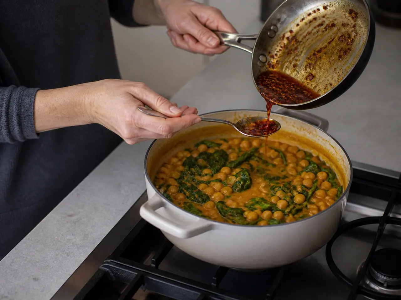 Hands stirring ginger garlic and spices through softened onion