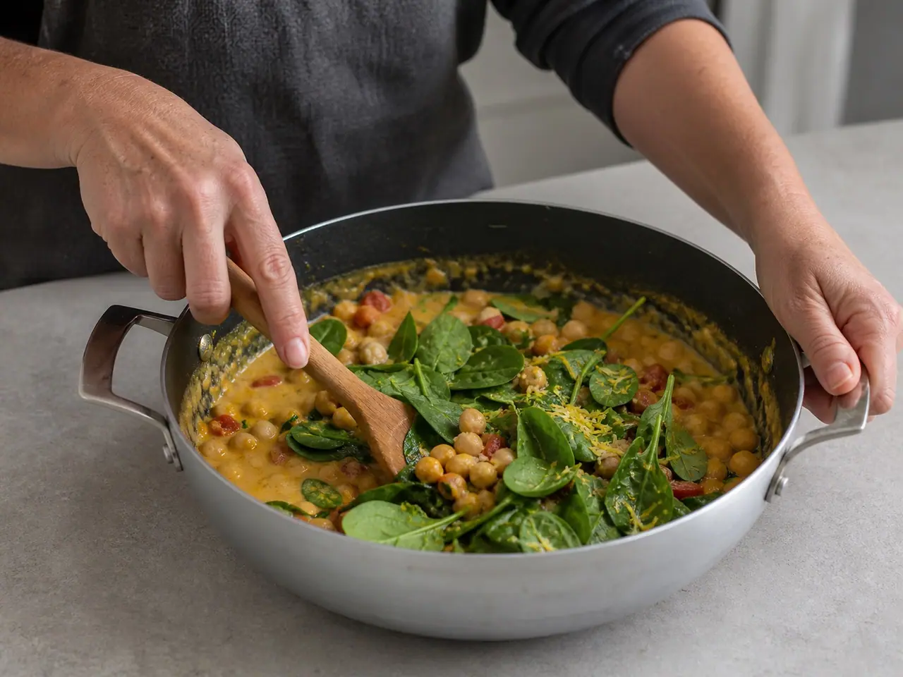 Hands stirring toasted spices into onion in a wide saucepan