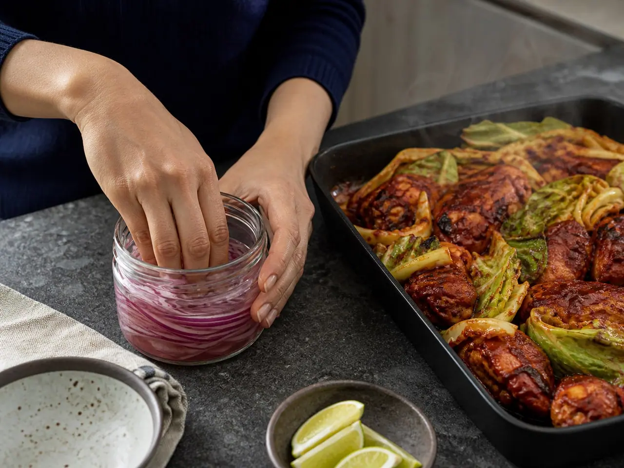 Hands stirring gochujang chicken and cabbage in a wide pan during cooking