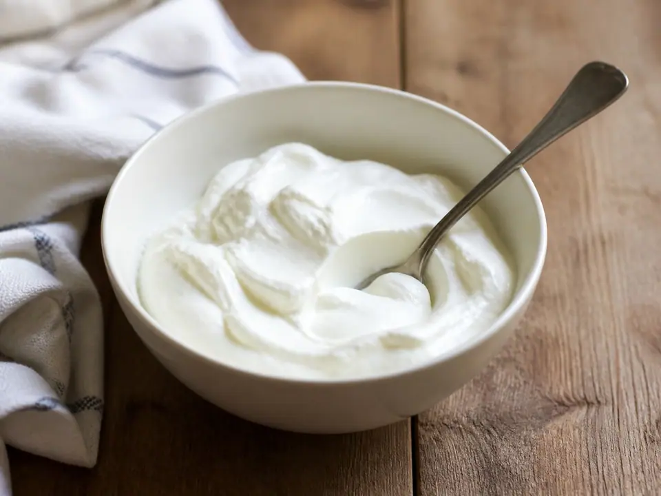 Thick plain Greek yogurt in a ceramic bowl with a spoon