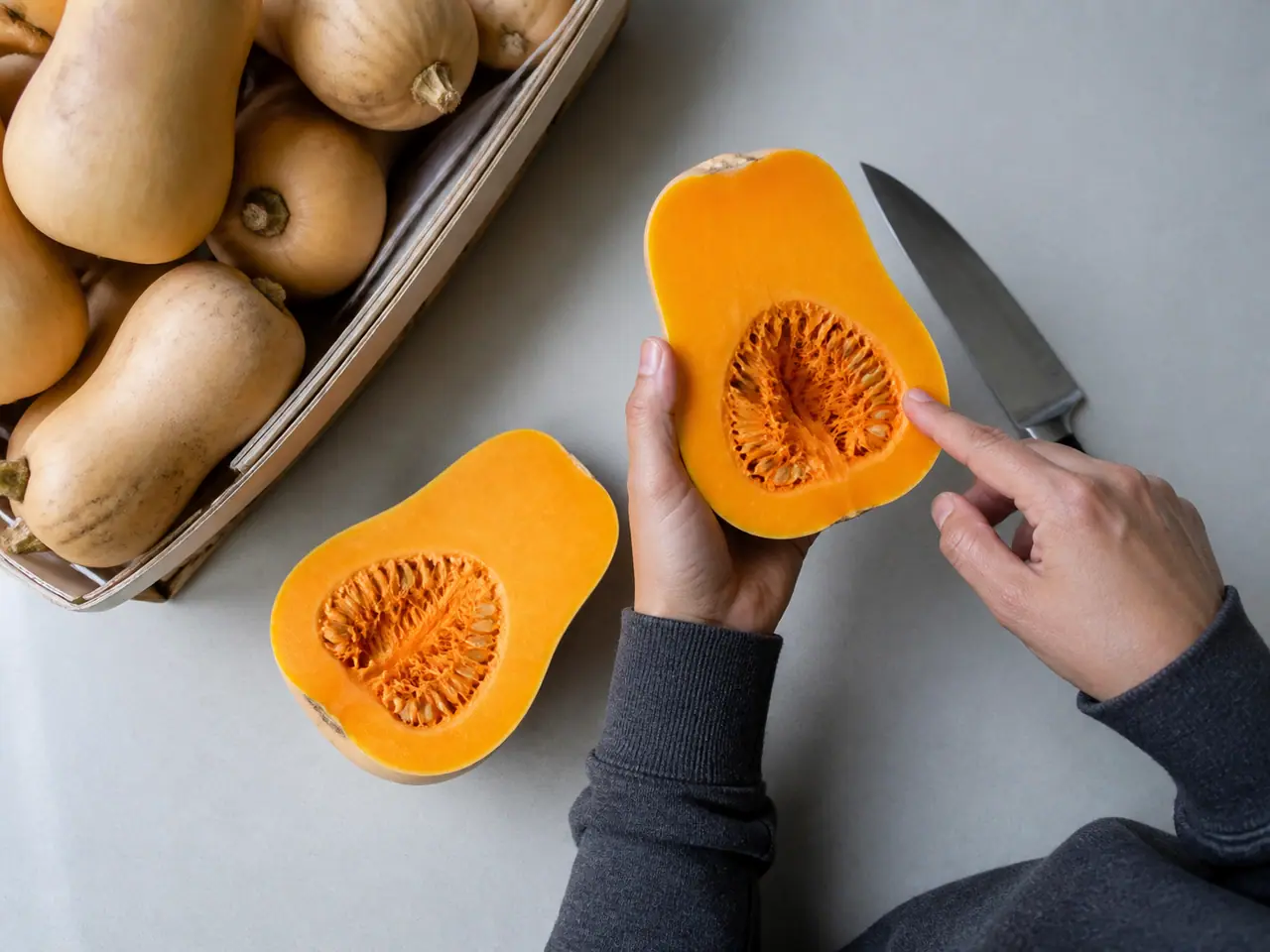 Hands comparing butternut squash necks and seed cavity size