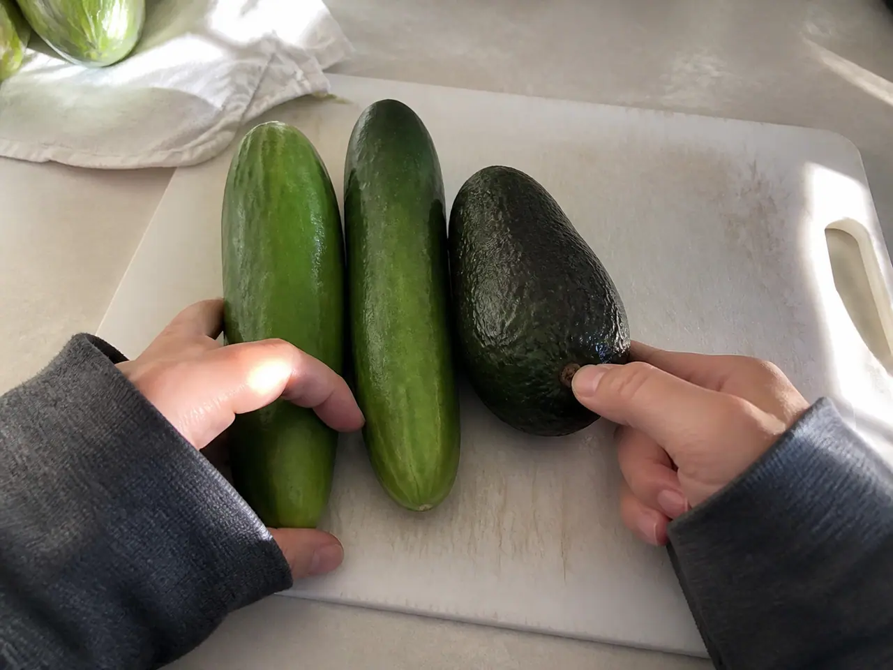 Hands pressing cucumber ends to check crispness