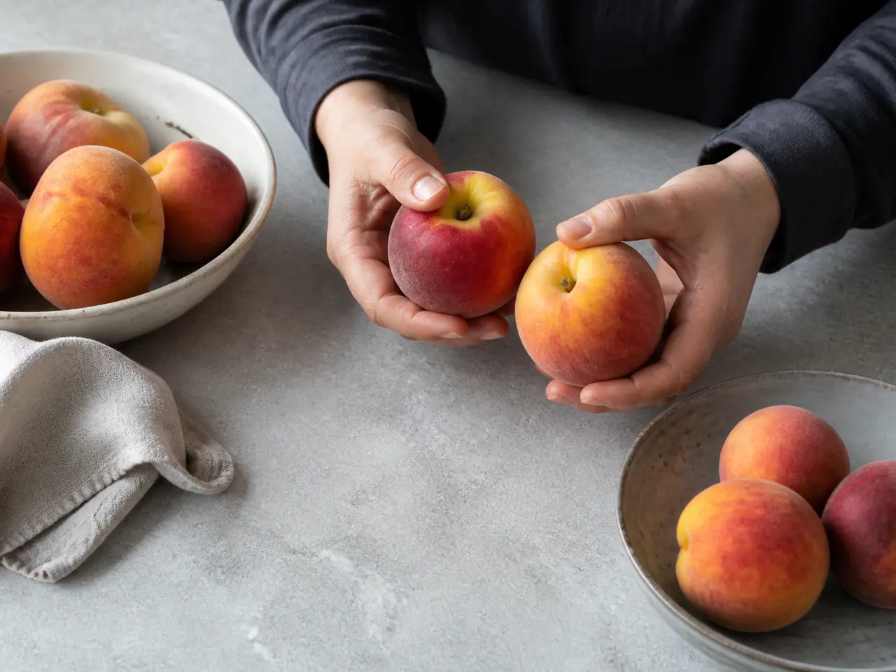 Hands checking peach fragrance and firmness near the stem