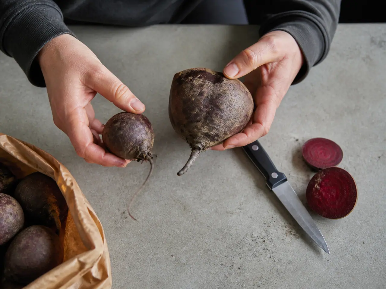 Hands comparing beetroot size and firmness before buying