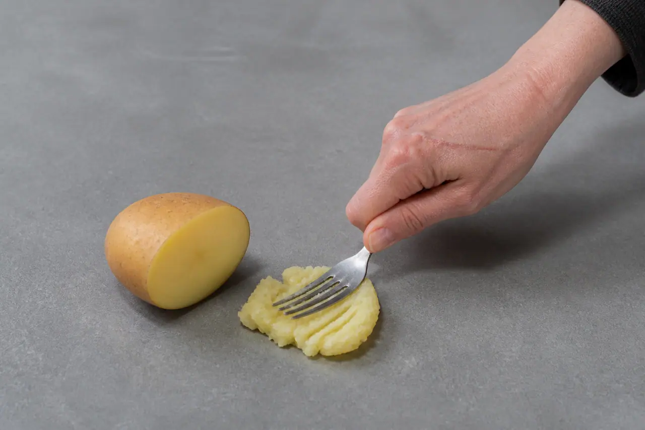 Hands comparing potato cut faces and pressing one piece to judge texture
