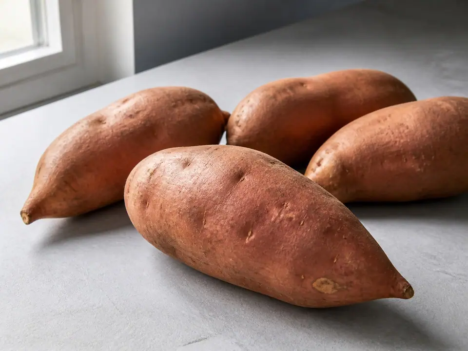 Firm sweet potatoes arranged on a cool kitchen surface