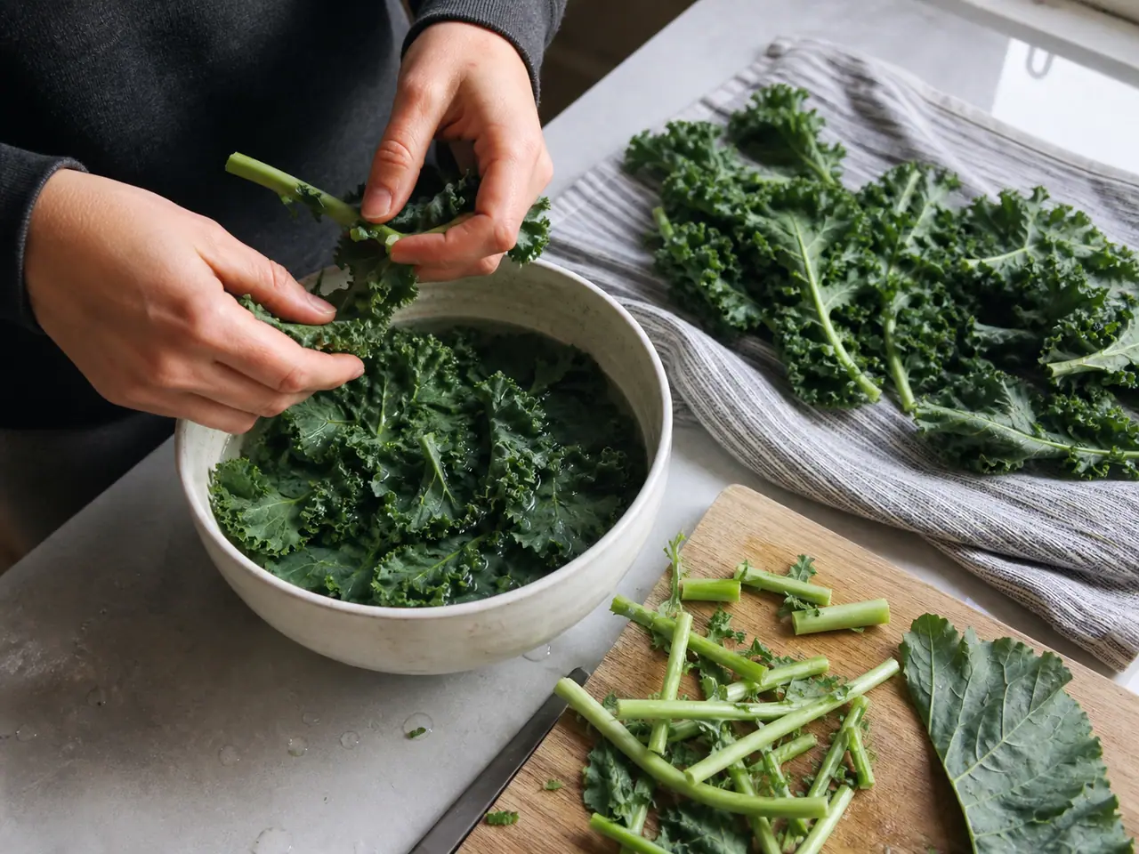 Hands stripping and drying kale leaves before storage