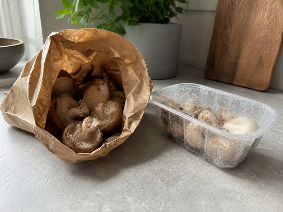 Mushrooms stored dry in a paper bag beside a damp plastic pack