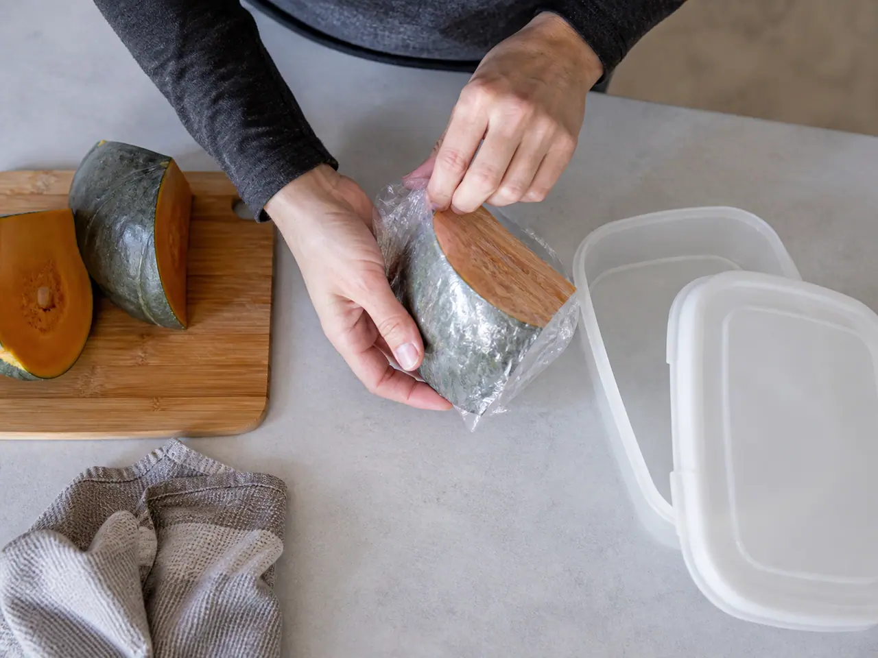 Hands wrapping the cut face of squash before refrigerator storage