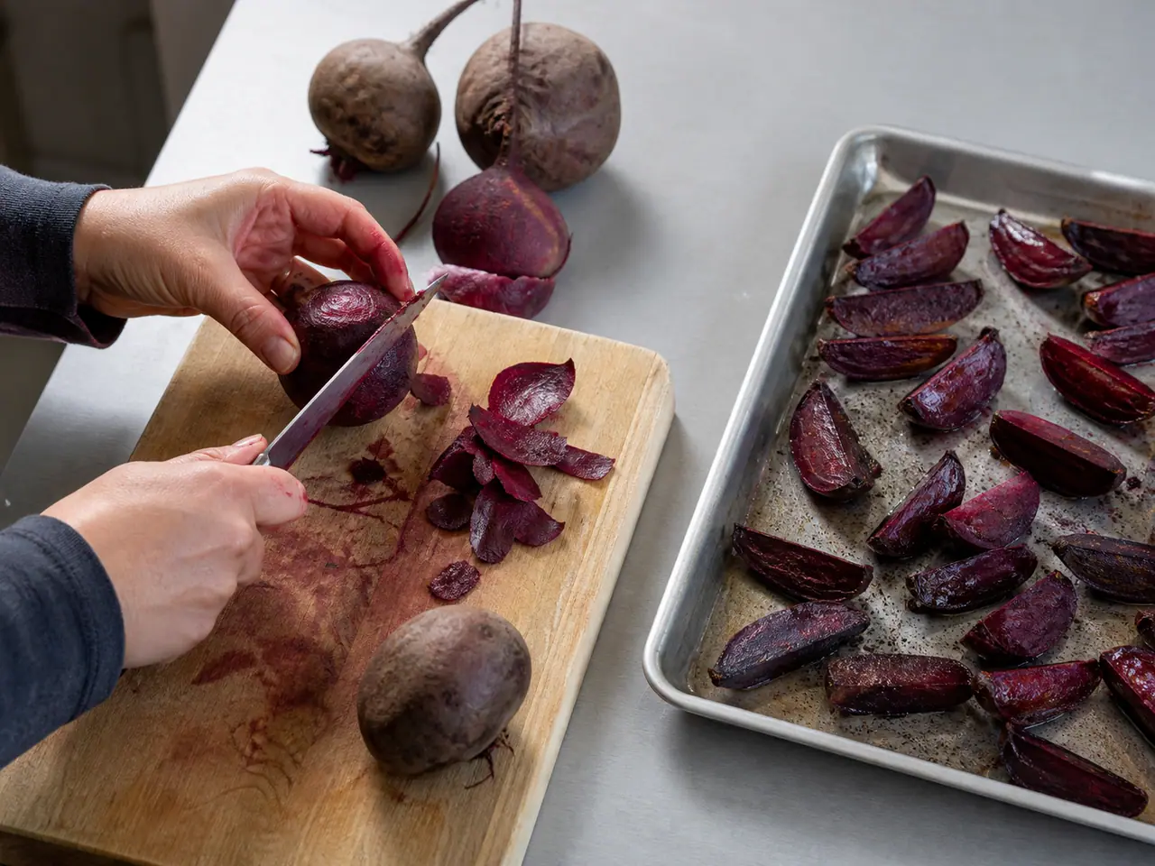 Hands cutting raw beetroot before comparing it with cooked pieces