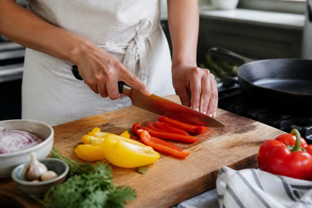Hands slicing red and yellow peppers for a hot skillet