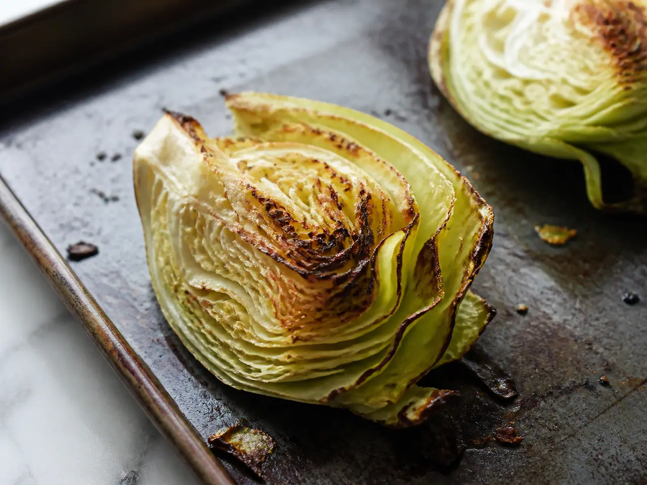 Cabbage wedge browning on a hot metal tray in the oven