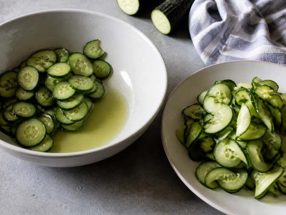 Cucumber slices releasing water beside a dry dressed salad