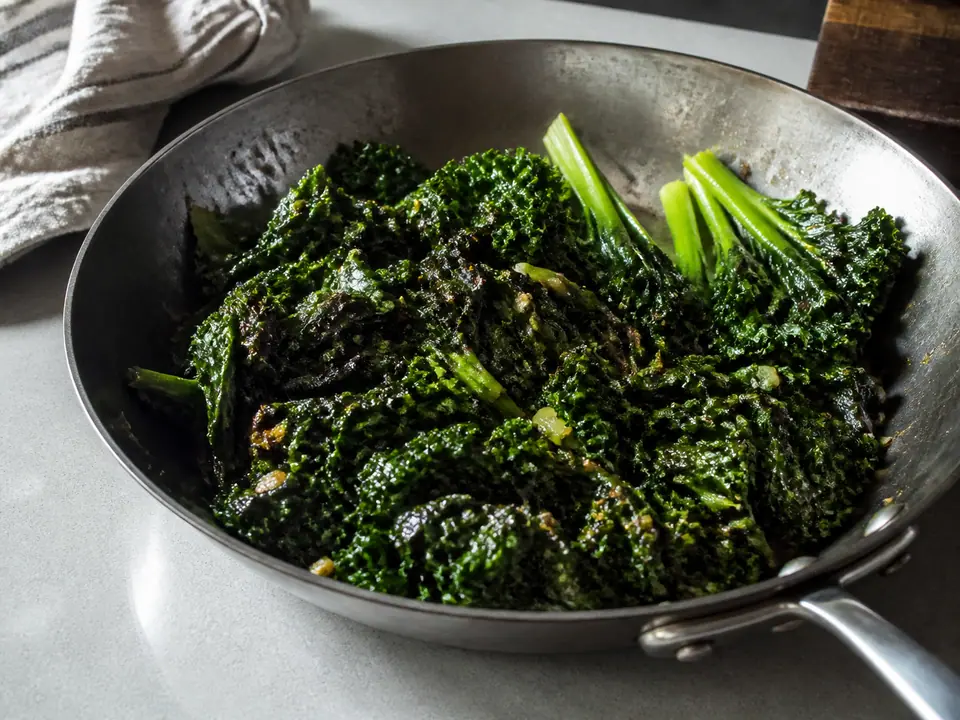 Tender browned kale beside a pan of tough quickly stirred leaves