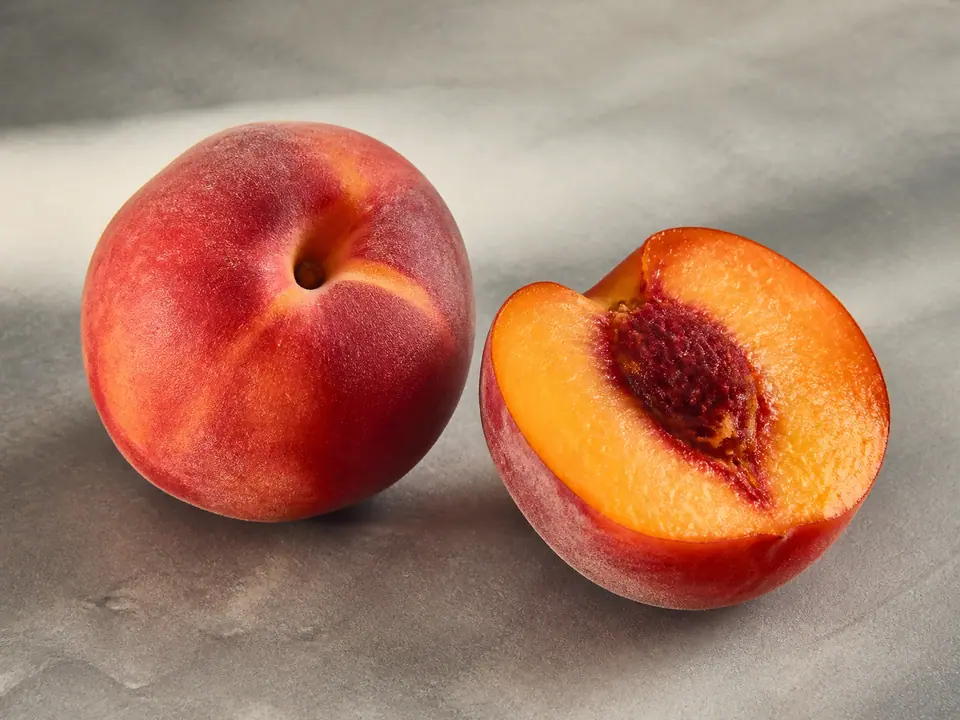 Fragrant firm peach beside a soft ripe peach cut open