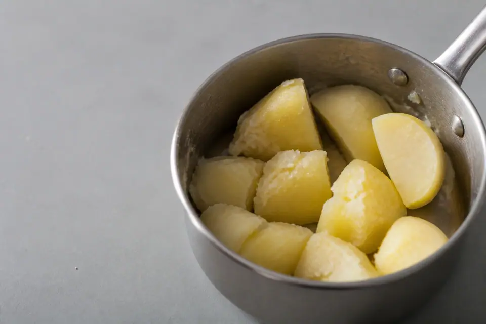 Potatoes with broken edges beside a firm centre piece in a saucepan