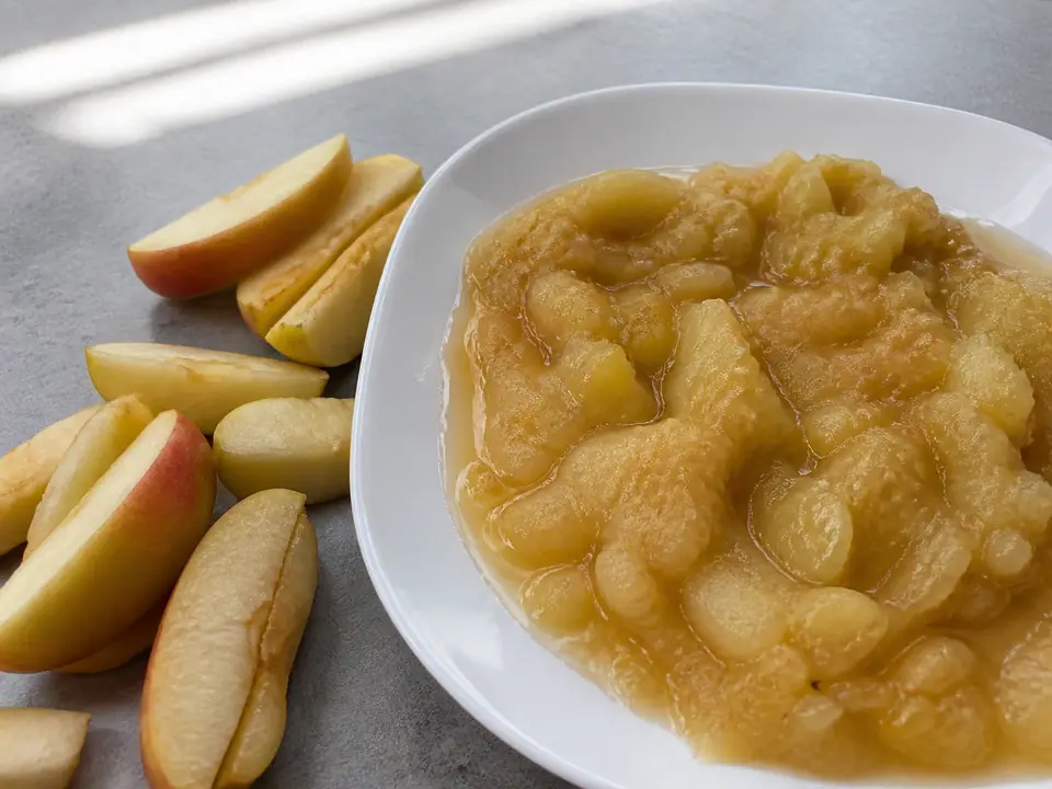 Apple slices beside a dish of collapsed apple sauce